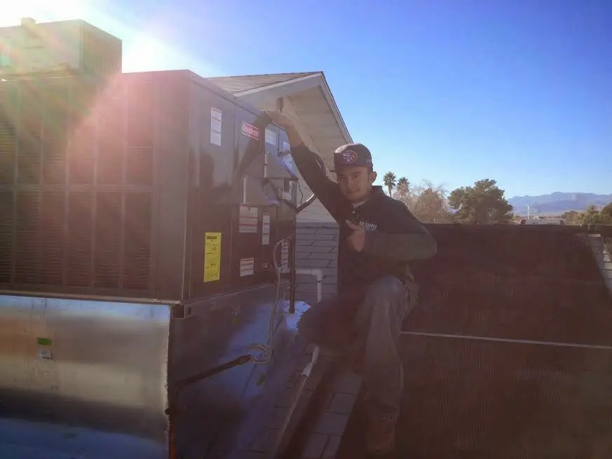 HVAC technician performing Air Duct Repair on a rooftop unit in London Grove